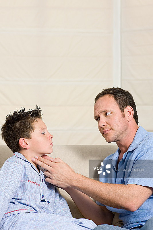 父亲检查儿子的脖子图片素材