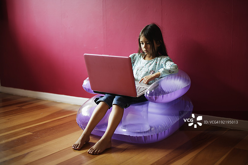 使用粉色笔记本电脑的五岁女孩图片素材