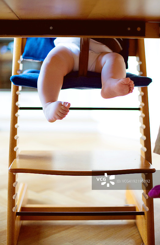 幼儿在餐椅上，桌子下的脚趾和腿图片素材