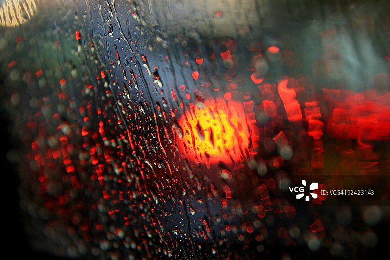 雨滴落在车窗上，看着交通灯图片素材