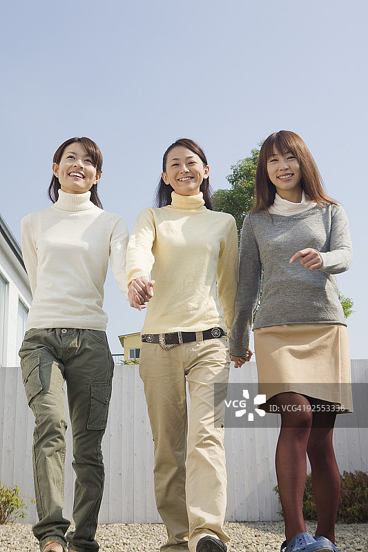 三名年轻女子在前院散步图片素材