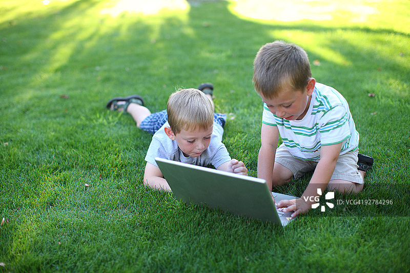 两个小男孩在户外使用笔记本电脑图片素材