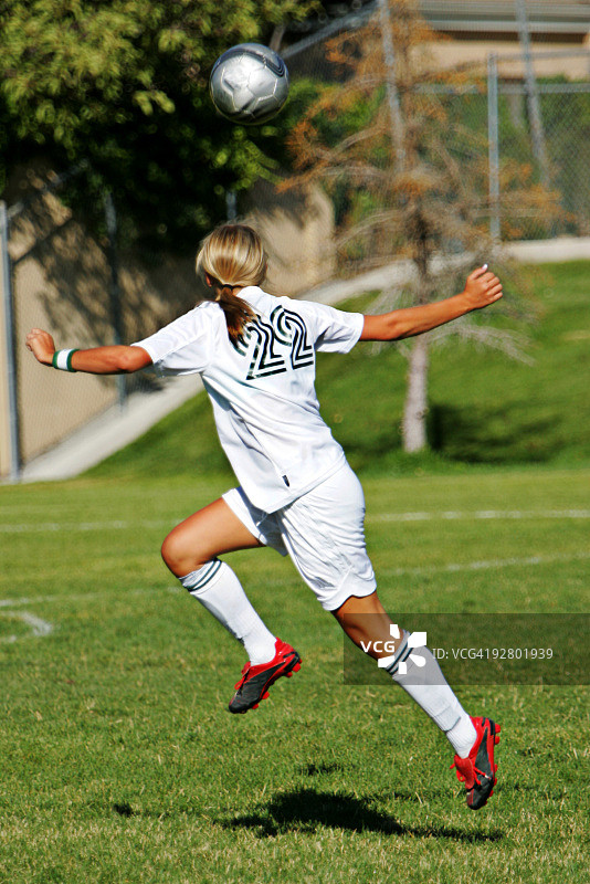 有魅力的女足球运动员在球下准备头球图片素材