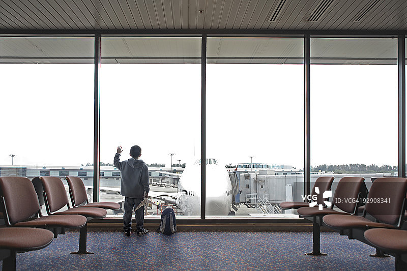 男孩在机场向窗外看图片素材