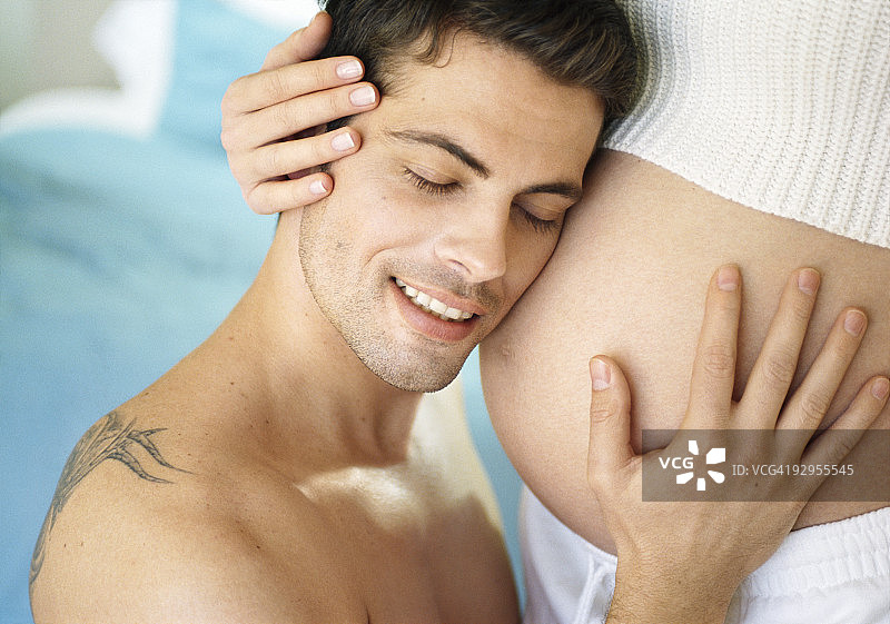 男人爱抚并倾听怀孕妻子的肚子图片素材