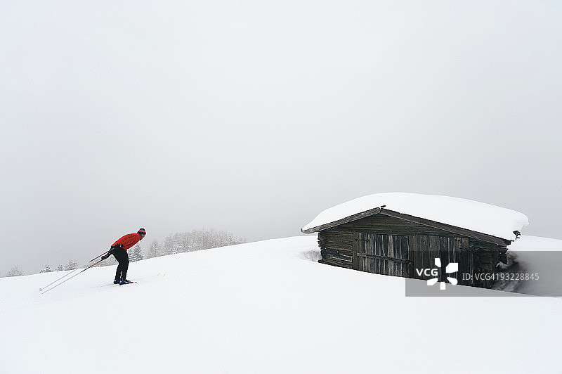 意大利南蒂罗尔：男子越野滑雪，背景是小木屋图片素材