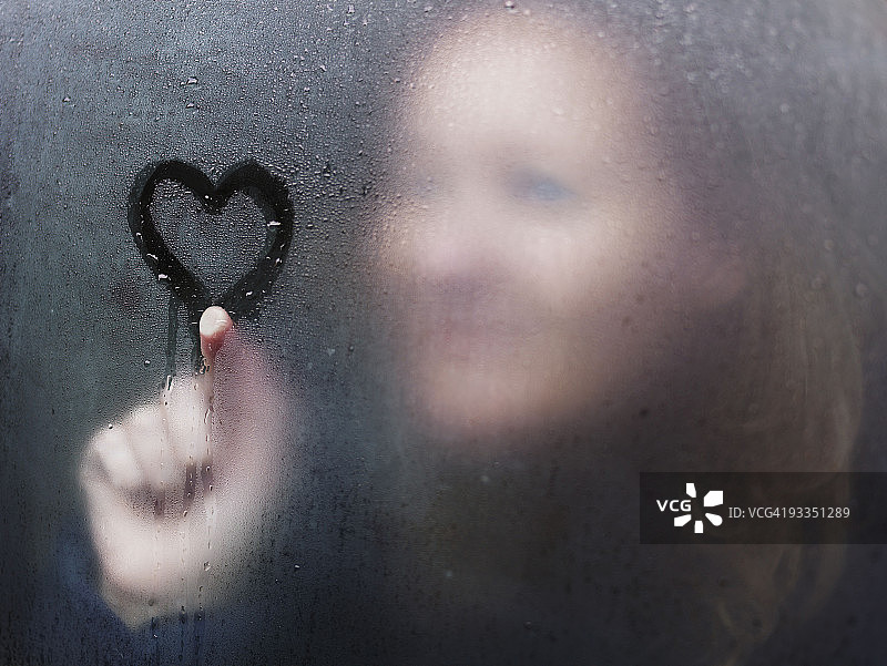 下雨天，女人在窗户上画心图片素材