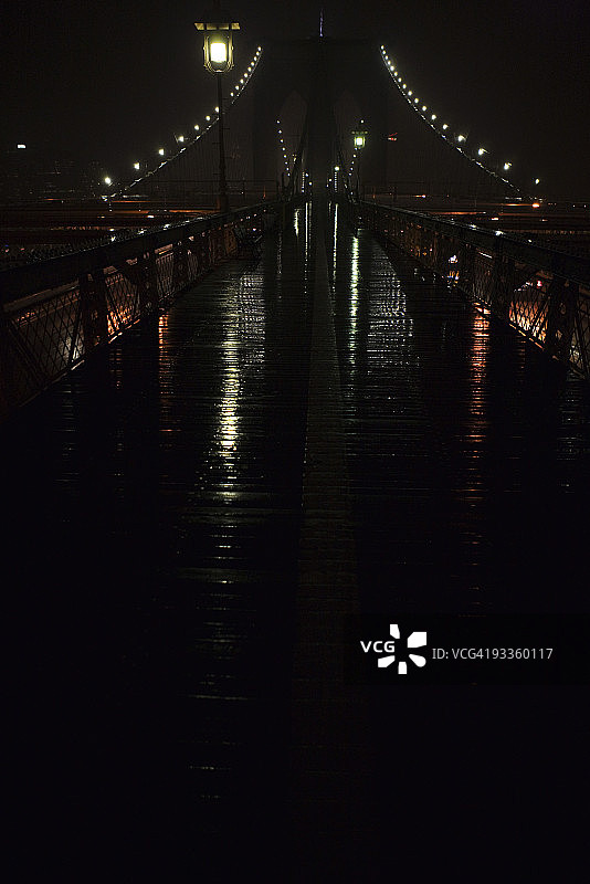 雨夜中湿漉漉的布鲁克林大桥人行道，美国纽约市图片素材