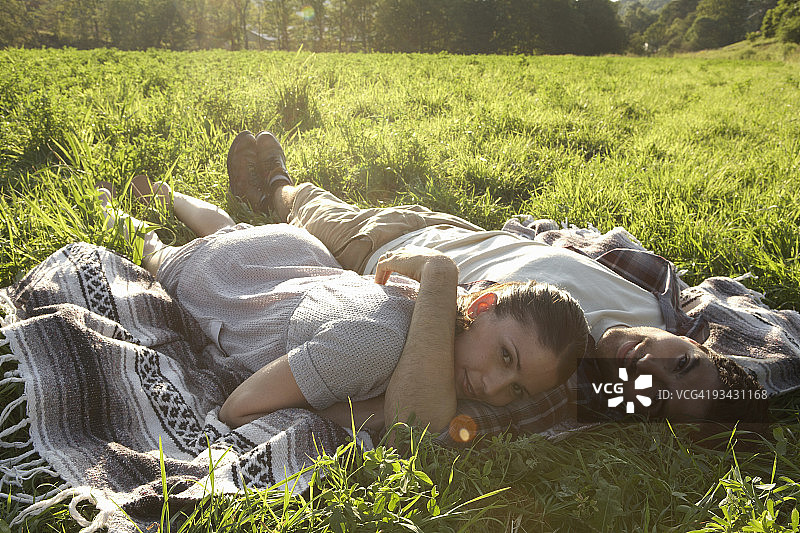 躺在田野毯子上的年轻情侣图片素材