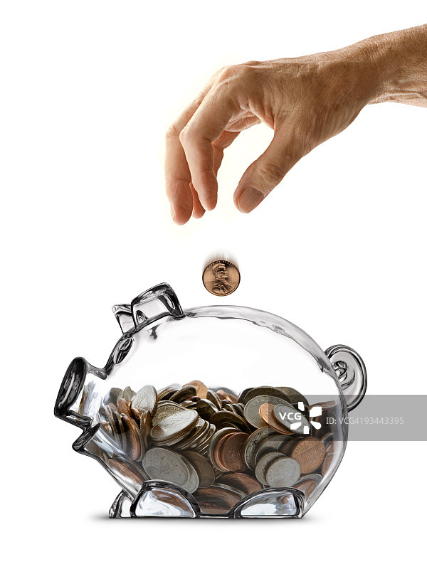 老年人的手将硬币投入半满的透明小猪存钱罐图片素材