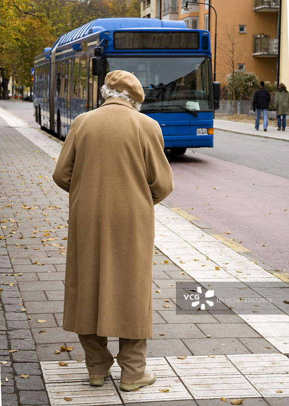 老年妇女正在等待一辆驶来的蓝色巴士图片素材