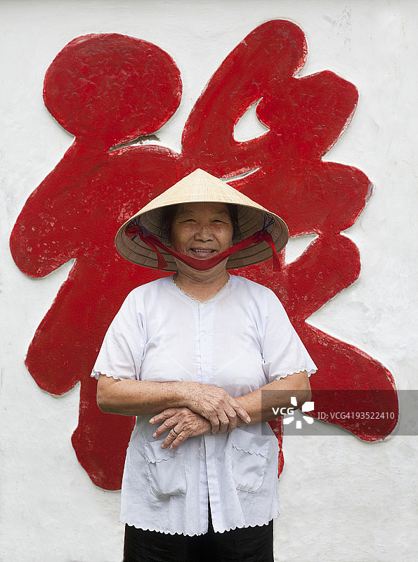 站在墙附近的年长越南女士图片素材