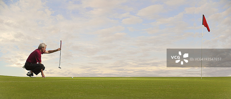正在瞄准推杆的中年高尔夫球手图片素材
