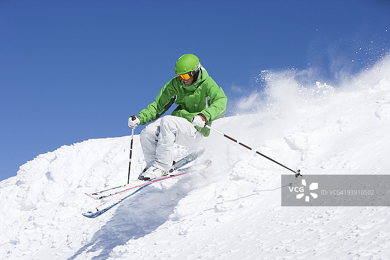 穿着绿色衣服的男人在非滑雪道上滑雪图片素材