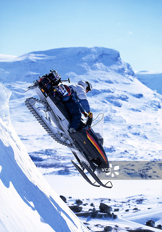 滑雪者在雪地摩托上跳跃图片素材