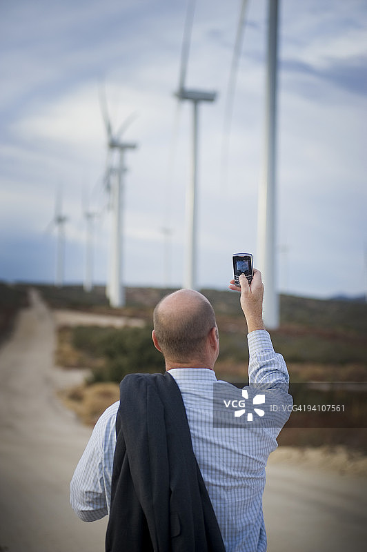 在风力发电场使用手机的商人图片素材