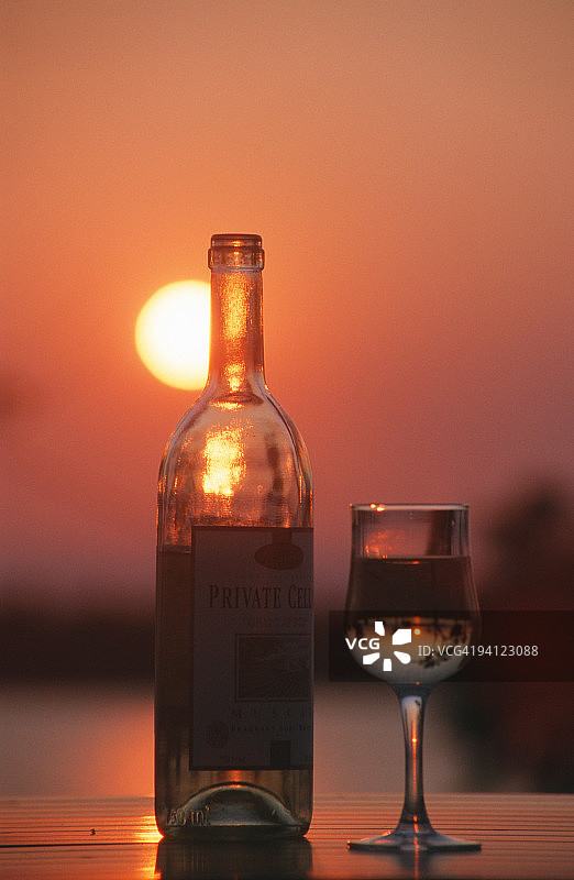 夕阳下的葡萄酒瓶与酒杯：赞比亚卡里巴湖切特岛图片素材