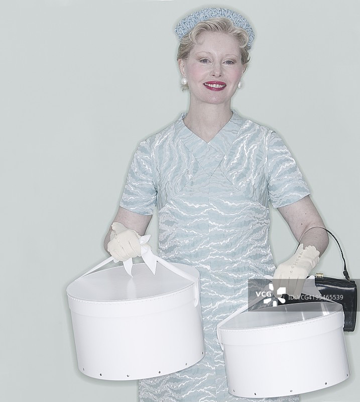 一位身穿20世纪50年代服装，手提帽盒的女人图片素材