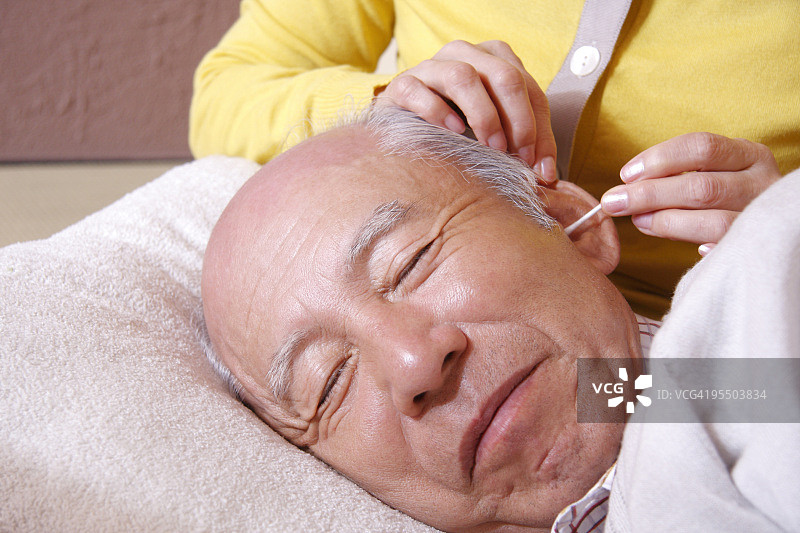 年长的妇女清洁年长男人的耳朵图片素材