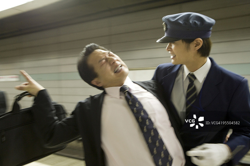 列车员在站台上搀扶着醉酒的商人，动态模糊图片素材