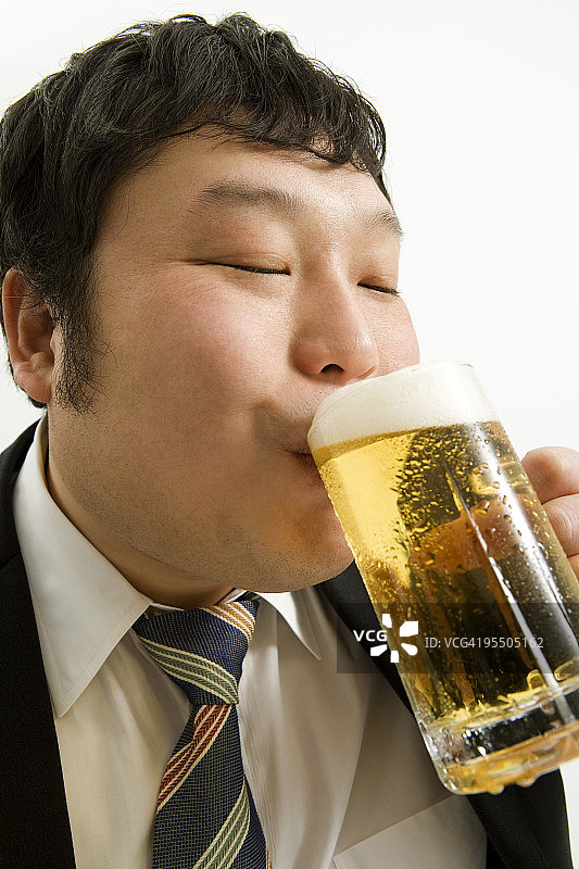 超重的男人正在喝一杯啤酒图片素材