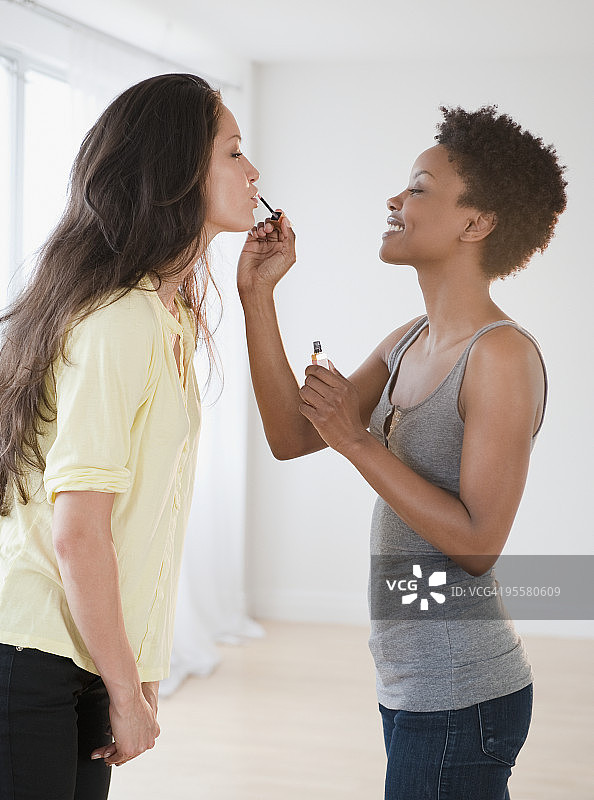 女人给朋友涂唇彩图片素材