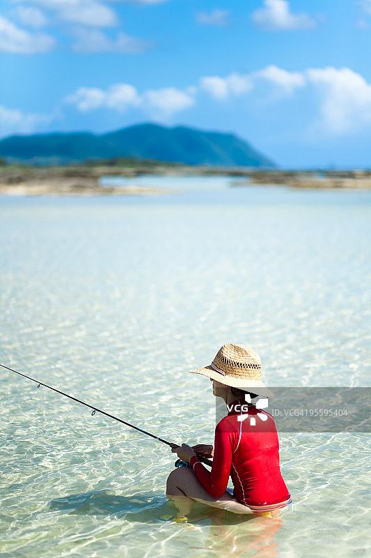 女孩在冲绳清澈的热带水域钓鱼图片素材