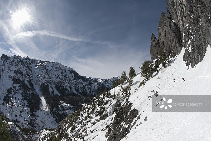 在科罗拉多州尤雷附近，两个年轻男人在蓝色天空下穿着雪鞋在山景中行走图片素材