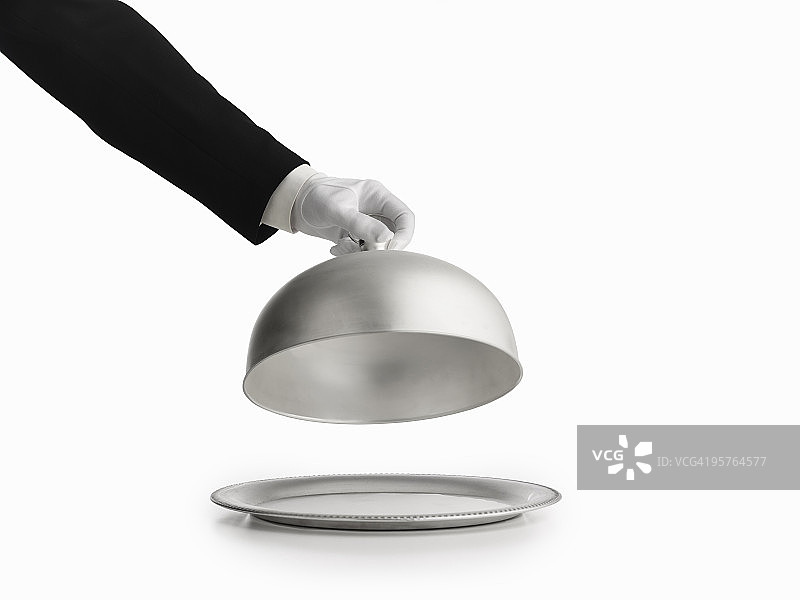 戴手套的手从盘子上拿起银色盖子图片素材