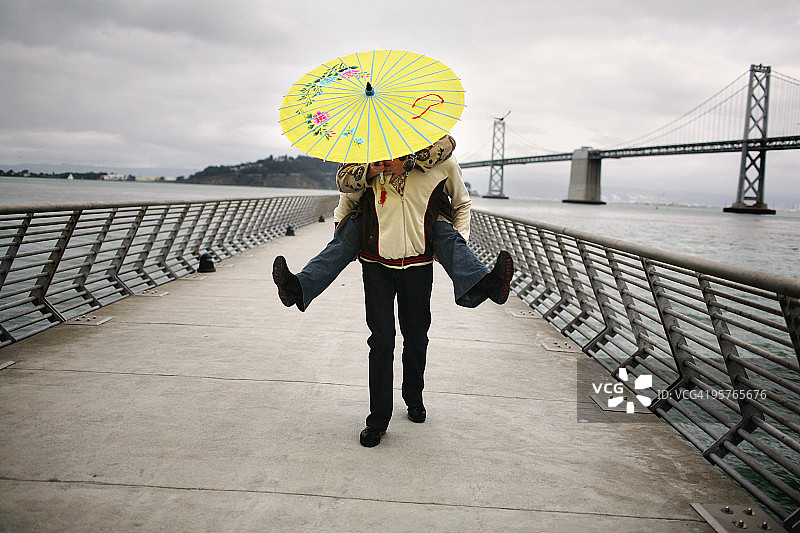 男人为拿着黄色雨伞的女人撑伞图片素材