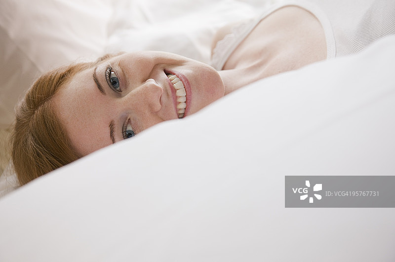 在床上对着镜头微笑的女人图片素材