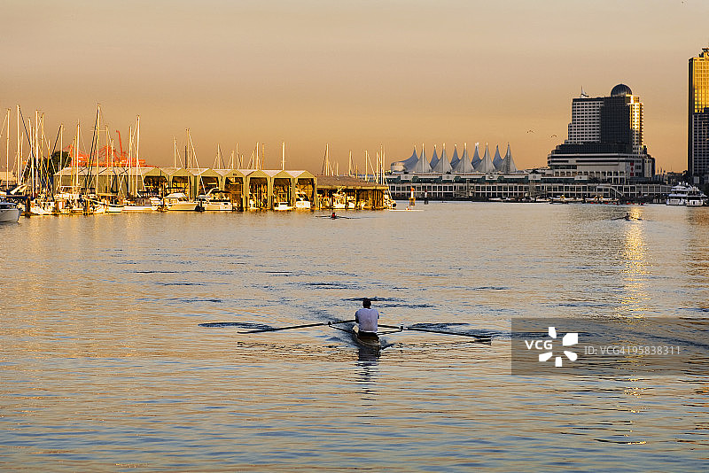 男人在城市海港划船，日落时分图片素材