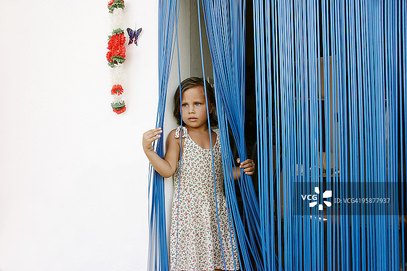 站在蓝色窗帘门口的女孩图片素材
