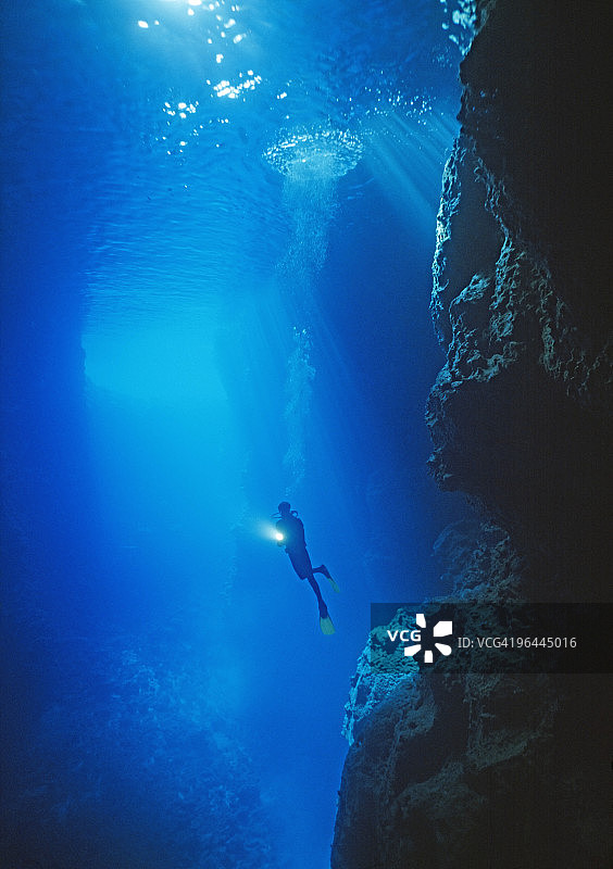 潜水员在大型海底洞穴中打光图片素材