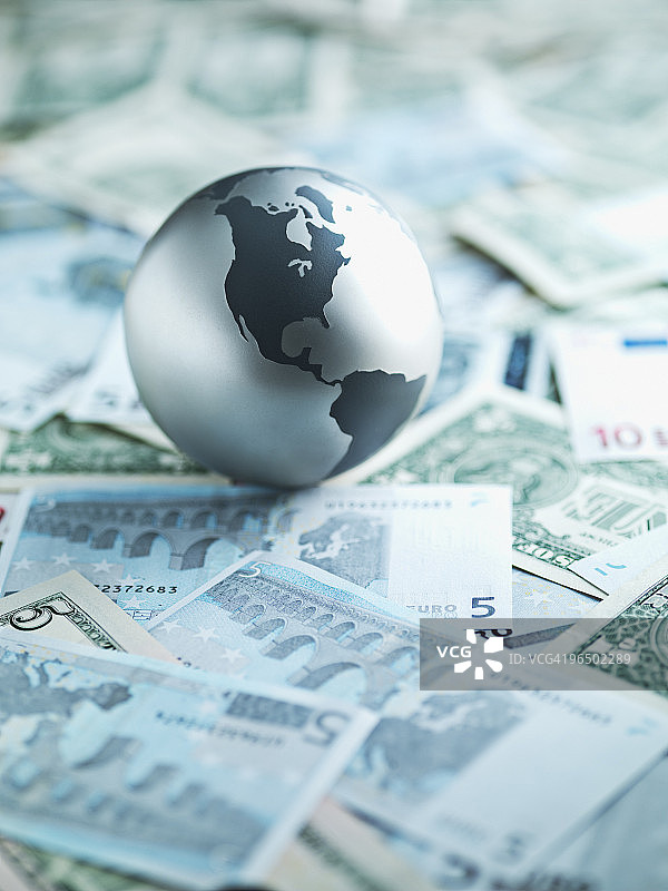 金属地球仪置于纸币上图片素材
