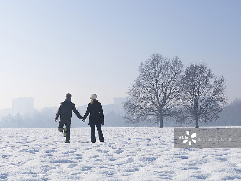 情侣在雪地中走向城市天际线图片素材