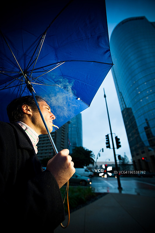 打伞吸烟的男人图片素材