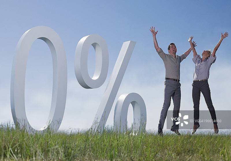 情侣在田野中跳跃旁有百分号图片素材
