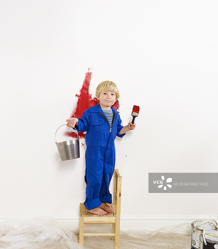 幼儿男孩把墙壁涂成红色图片素材
