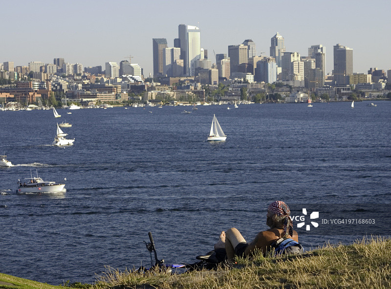 戴着头巾的骑自行车的人看着湖和西雅图图片素材