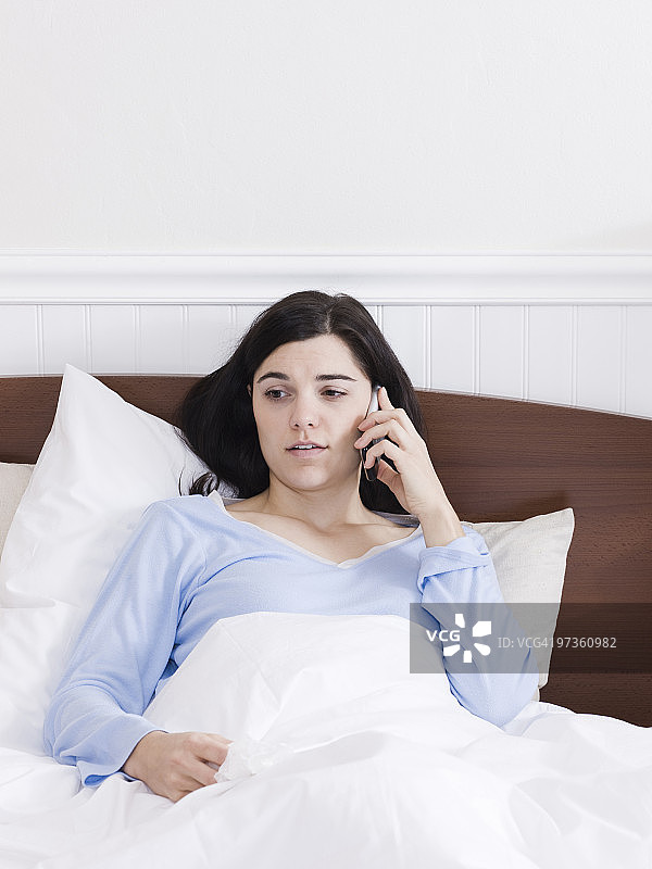 美国犹他州奥勒姆市：床上用手机聊天的年轻患病女人图片素材
