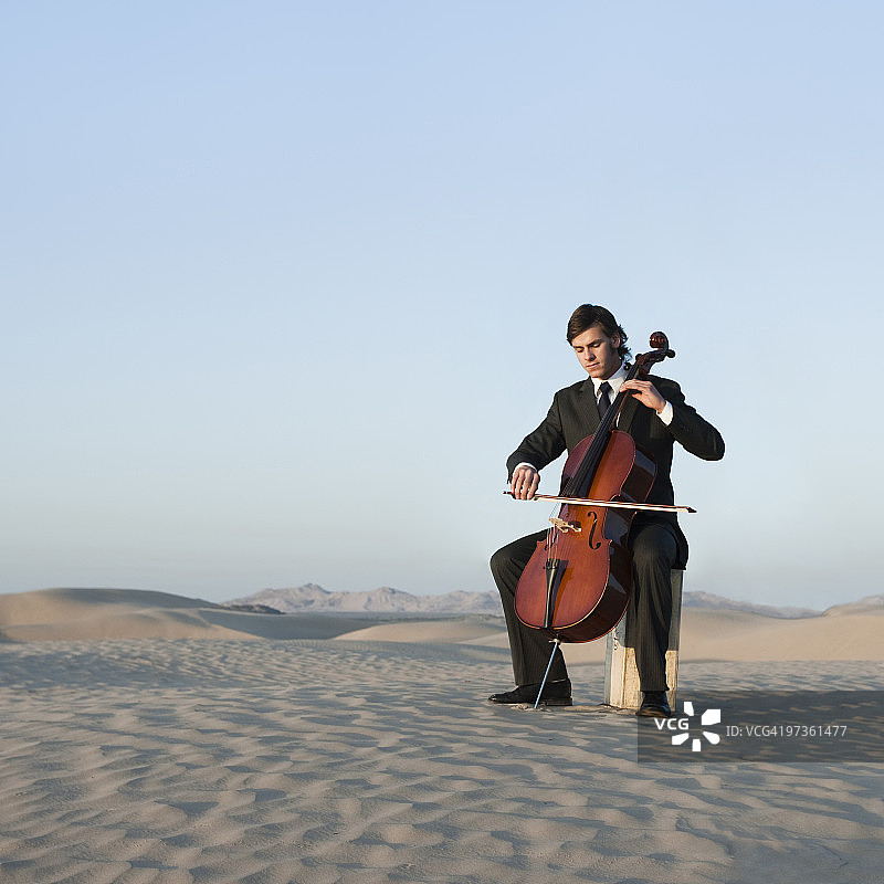 美国犹他州小撒哈拉沙漠中演奏大提琴的年轻男人图片素材