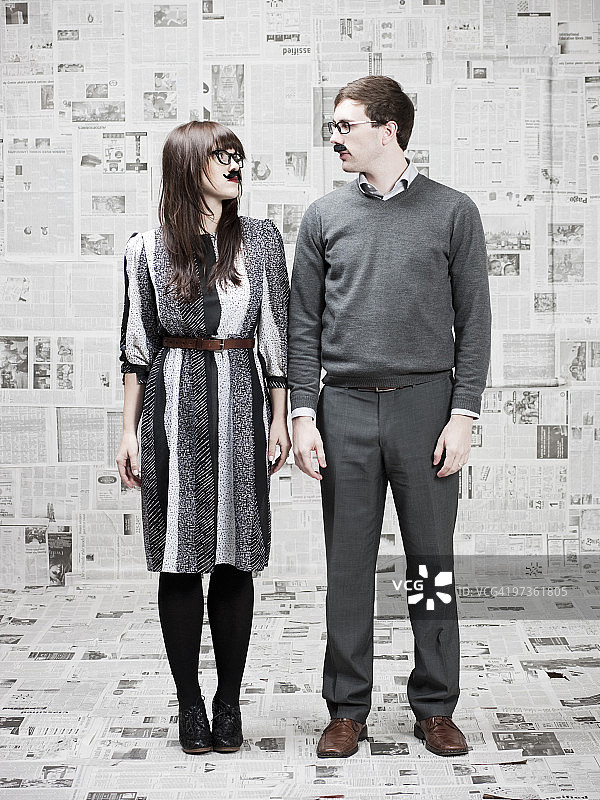 两个戴着假胡子的年轻人在堆满报纸的房间里，工作室拍摄图片素材