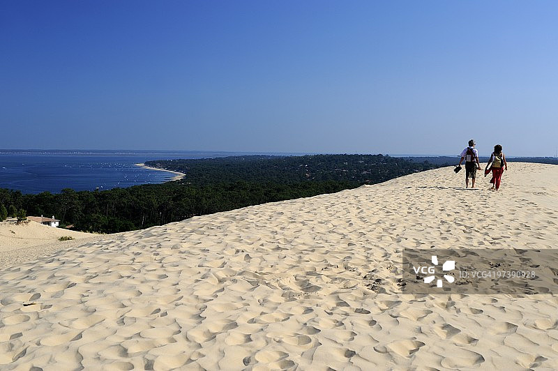 情侣在法国阿卡雄湾的皮拉沙丘上散步图片素材