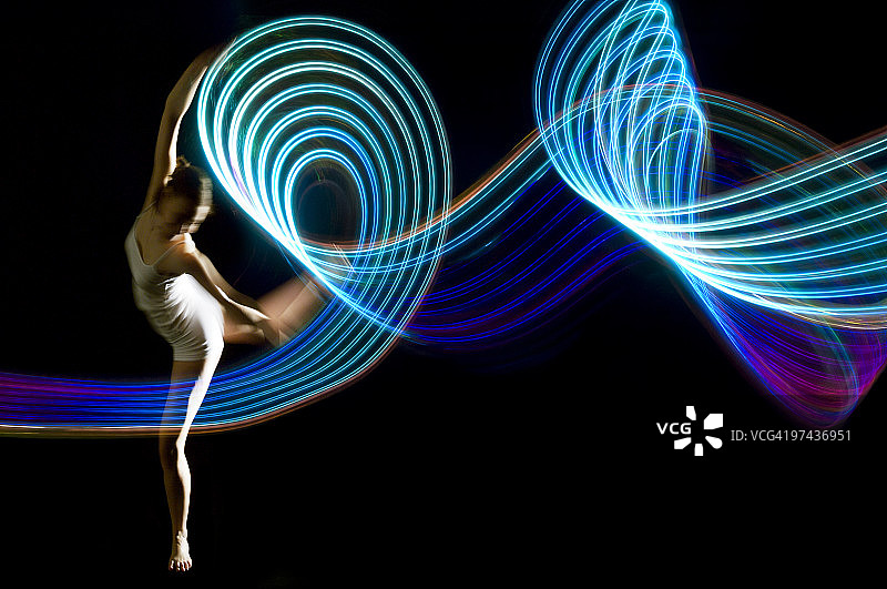 在蓝色光迹中旋转的优雅舞者图片素材