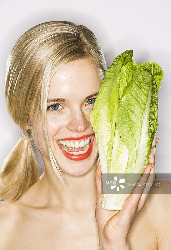 年轻女人笑着拿着生菜叶图片素材