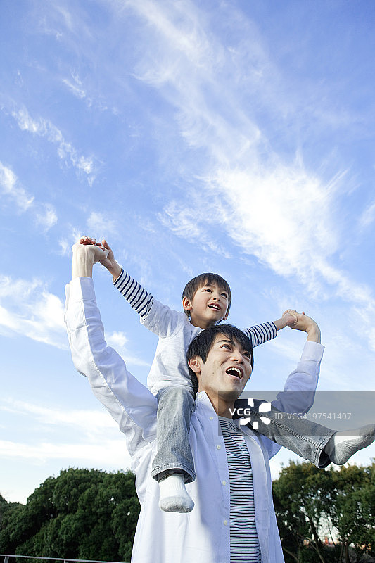 父亲肩上扛着儿子，低角度拍摄图片素材