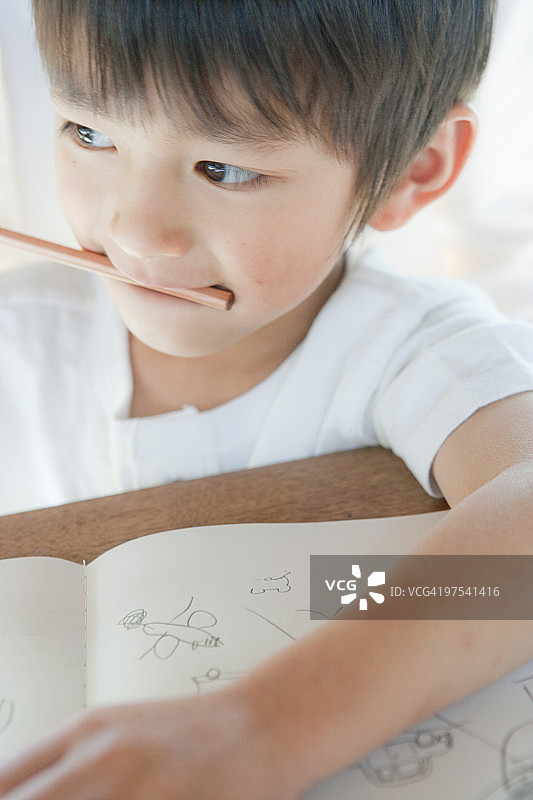 特写：一个4-5岁的男孩正在咬铅笔图片素材