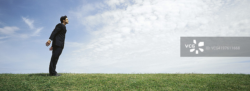 站在草地上张开双臂迎风的商人图片素材
