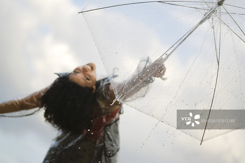 年轻女人举着伞，对着镜头微笑图片素材